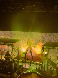 a woman on stage with a yellow light behind her