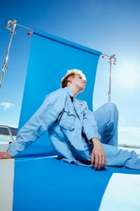 a young man laying on a blue background