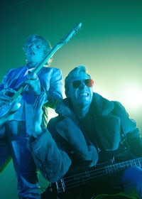 two men on stage with guitars and sunglasses