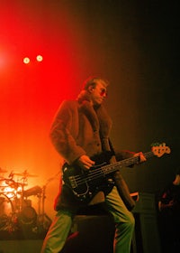 a man in a fur coat playing a bass on stage