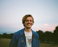 a young man smiling in front of a field