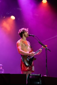 a shirtless man on stage with a guitar