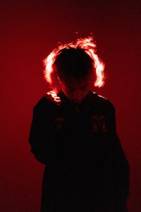 a person wearing a black jacket with a red light behind them