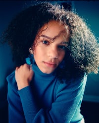 a young woman with curly hair posing for a photo