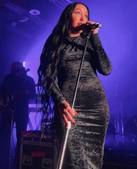 a woman in a black dress singing into a microphone