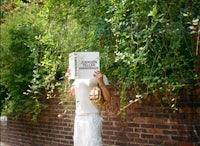 a man holding a book in front of a brick wall