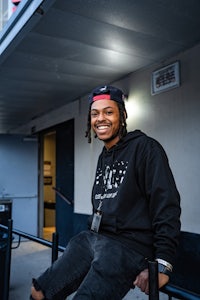 a young man in a black hoodie sitting on a railing