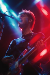 a man playing a guitar in front of red lights