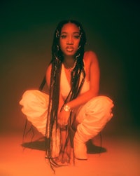 a woman with dreadlocks crouching down in front of an orange light