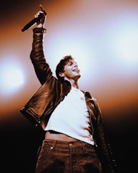 a man in a leather jacket is holding a microphone