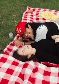 a man and woman laying on a picnic blanket