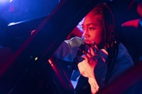 a woman in a car with dreadlocks sitting in the driver's seat