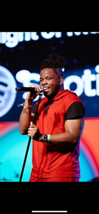 a man in a red shirt singing into a microphone