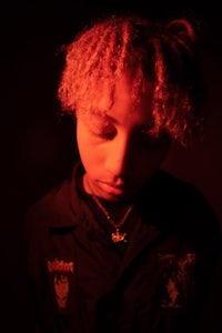 a young man with curly hair in a dark room