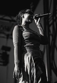 a black and white photo of a woman singing into a microphone