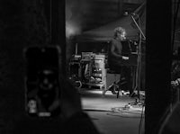 a black and white photo of a man on stage with a cell phone