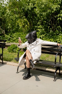 a woman is sitting on a park bench with a phone in her hand