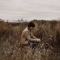 a man sitting on a chair in a field