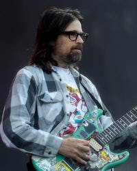 a man with glasses and a beard playing an electric guitar