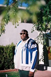 a man in a blue and white jacket standing in front of a house