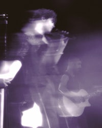 a blurry image of a man playing an acoustic guitar