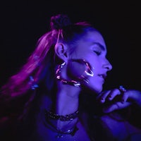 a woman wearing a purple hoop earring in front of a purple light