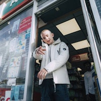 a man in a white jacket standing in front of a store