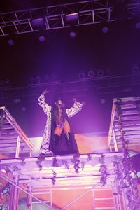 a woman standing on top of a stage with purple lights