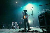 a man standing on stage with a guitar