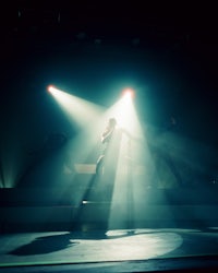 a woman performs on stage in front of a light beam