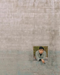 a man peeking out of a window in a wall