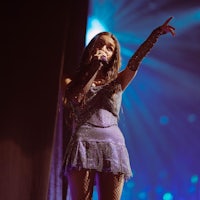 a woman in a purple dress singing into a microphone