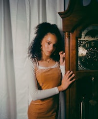 a young woman posing next to a grandfather clock