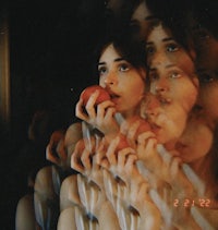 a woman is holding an apple in front of a mirror