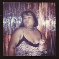 a woman in a leopard print dress holding a drink