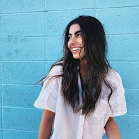 a woman wearing a white shirt and jeans standing in front of a blue wall