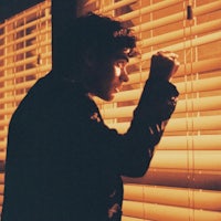 a man standing in front of a window with blinds