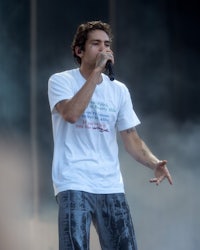 a man in a white t - shirt singing into a microphone