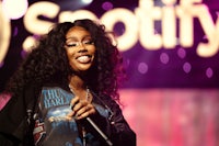 a woman is holding a microphone in front of a spotify sign