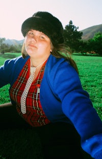 a woman in a plaid shirt sitting on the grass