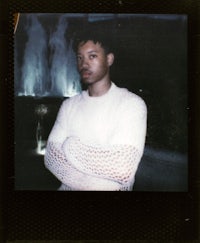 a man in a white sweater standing in front of a fountain