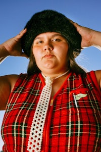 a woman wearing a plaid vest and hat