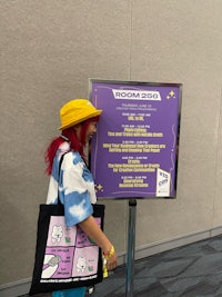 a woman standing in front of a sign with a poster