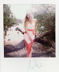 a woman is posing in front of a tree