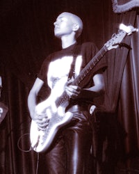 a man playing a guitar in front of a curtain