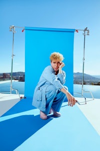 a woman crouching in front of a blue backdrop