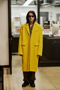 a person in a yellow coat standing in an office