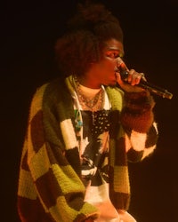 a man in a sweater singing into a microphone