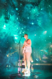 a woman on stage with a guitar in front of a starry sky