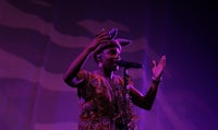 a woman in a colorful dress singing into a microphone